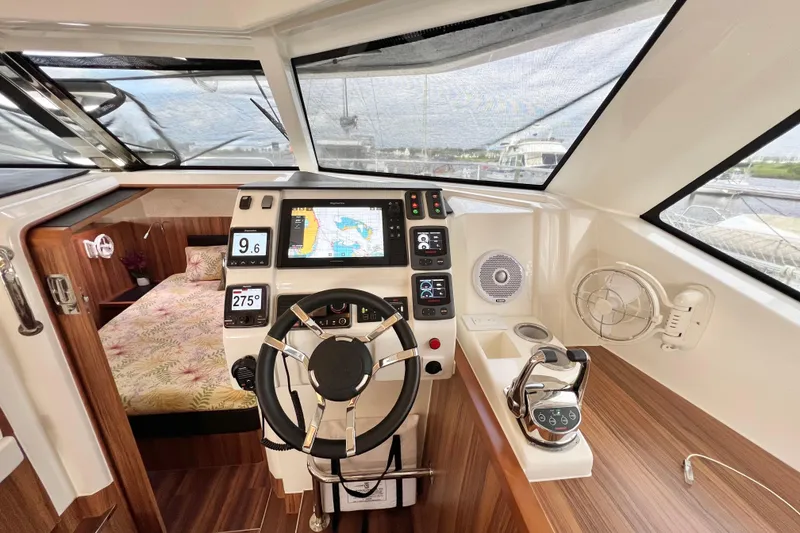 Slide: The Image of 2019 Aquila 44 yacht helm with navigation controls, steering wheel, and cabin view. - 56