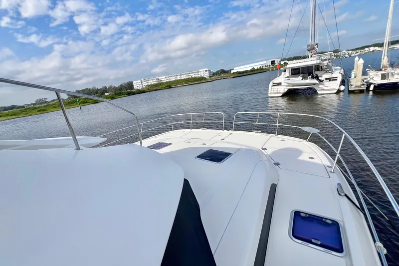 Slide: The Image of 2019 Aquila 44 yacht on calm water, with clear sky and marina view. - 7