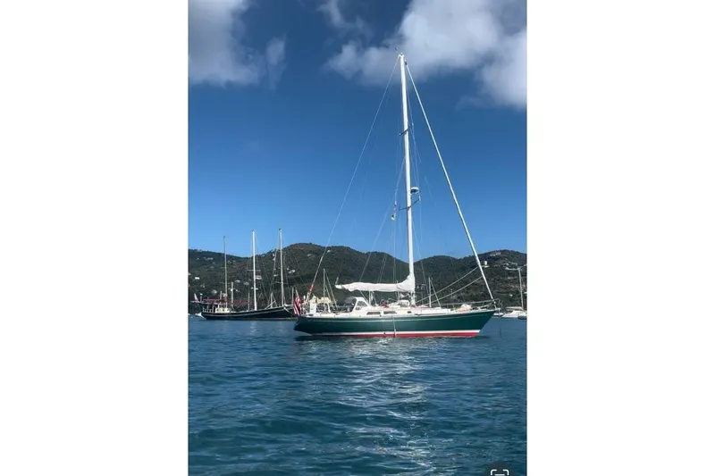 The Image of 1980 Alden 44 sailboat on calm water with scenic mountain backdrop. - 1