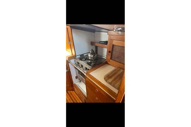 Slide: The Image of 1980 Alden 44 yacht kitchen with stove, wooden cabinetry, and cutting board. - 8