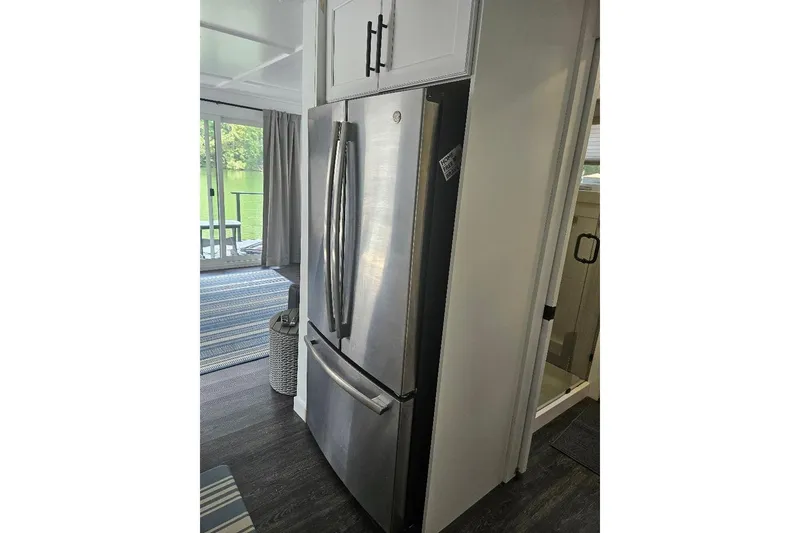 Slide: The Image of Modern kitchen interior of 2021 East Coast Houseboats Freedom 40, featuring stainless steel refrigerator. - 13