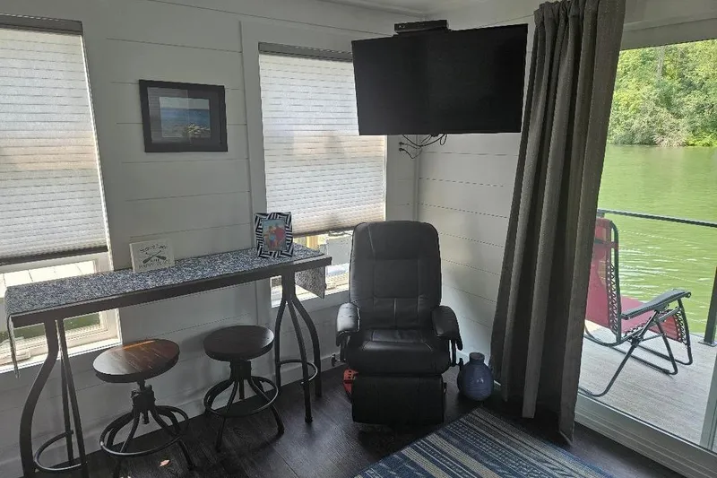 Slide: The Image of Interior of 2021 East Coast Houseboats Freedom 40 with seating, TV, and lake view. - 4
