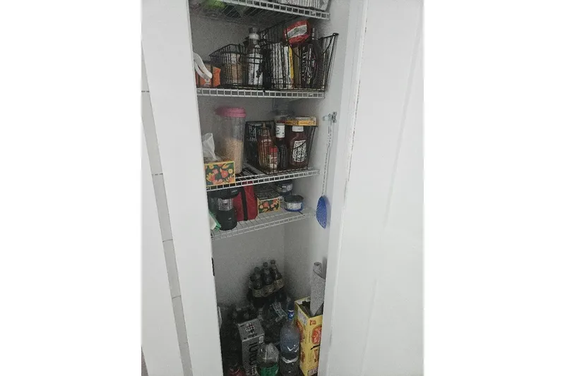 Slide: The Image of Pantry shelves with assorted food items and beverages on an East Coast Houseboats Freedom 40. - 8