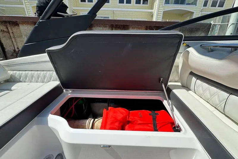 Slide: The Image of 2022 Regal LX2 boat storage compartment with life jackets and luxury seating. - 19