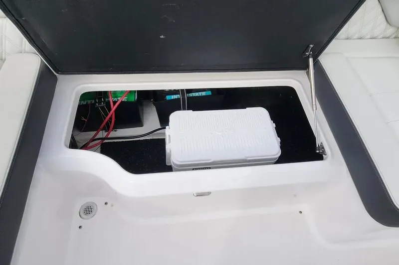 Slide: The Image of 2022 Regal LX2 boat storage compartment with cooler and battery cables. - 23