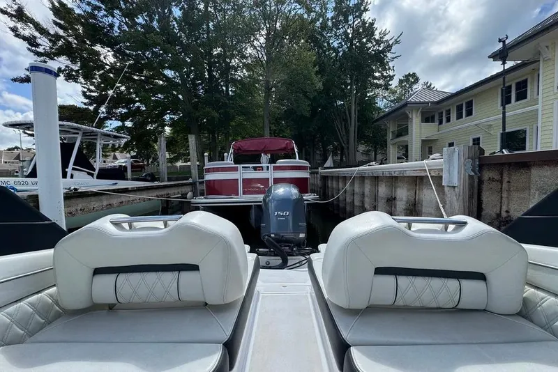 Slide: The Image of 2022 Regal LX2 boat interior with outboard motor, docked near waterfront homes. - 34