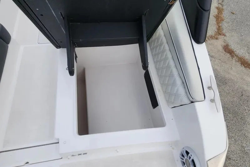 Slide: The Image of Open storage compartment on a 2022 Regal LX2 boat, featuring quilted seating and speaker. - 37