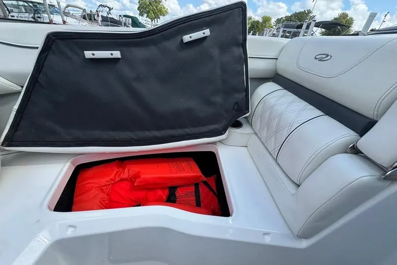 Slide: The Image of 2022 Regal LX2 boat seat storage with life jacket, open compartment, white upholstery. - 41