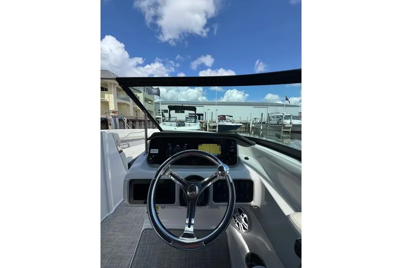 Slide: The Image of 2022 Regal LX2 boat dashboard with steering wheel, marina view, and clear blue sky. - 5