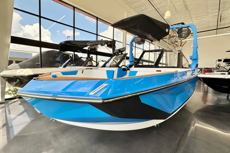 Slide: The Image of 2026 Nautique Super Air Nautique GS22 in showroom, vibrant blue exterior, modern design. - 1