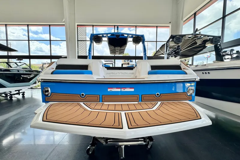 Slide: The Image of 2026 Nautique Super Air Nautique GS22 in showroom, rear view, blue and white design. - 2