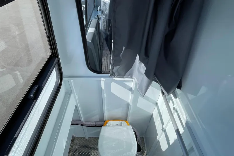 Slide: The Image of Interior of 2026 Hewescraft 270 ALASKAN ET HT boat, featuring compact restroom area. - 16