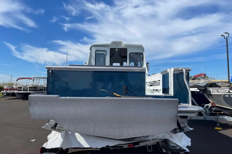 Slide: The Image of 2026 Hewescraft 270 Alaskan ET HT boat, blue and silver, parked outdoors under a clear sky. - 5