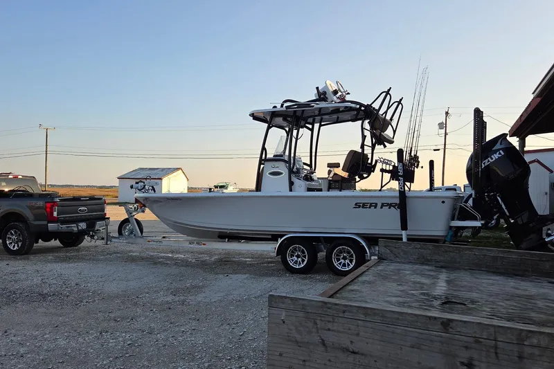 Slide: The Image of 2024 Sea Pro 250 Bay boat on trailer, parked beside a truck at sunset. - 13