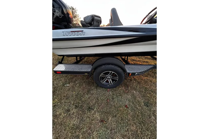 Slide: The Image of 2024 Triton 179 TrX boat on trailer, side view, parked on grass. - 0