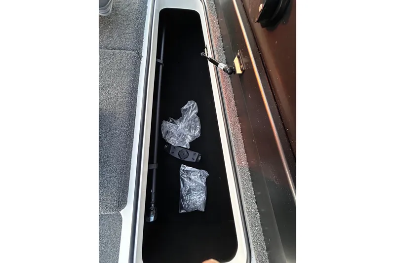 Slide: The Image of 2024 Triton 179 TrX storage compartment with fishing rod and accessories. - 17