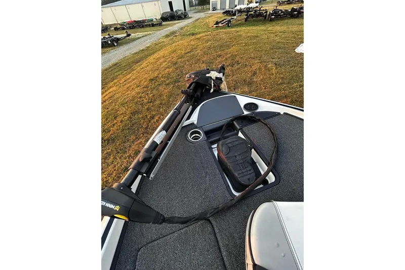 Slide: The Image of 2024 Triton 179 TrX boat deck with trolling motor and pedal, parked on grass. - 18