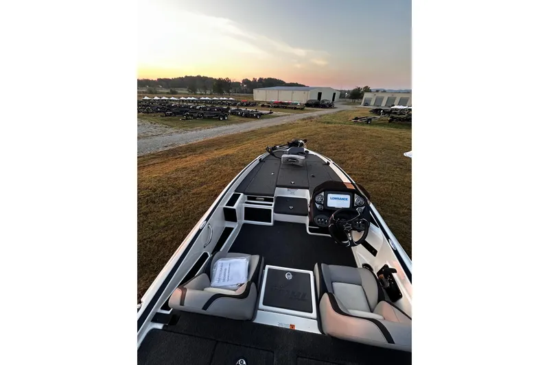 Slide: The Image of 2024 Triton 179 TrX boat interior with steering console, seats, and Lowrance display at sunset. - 2