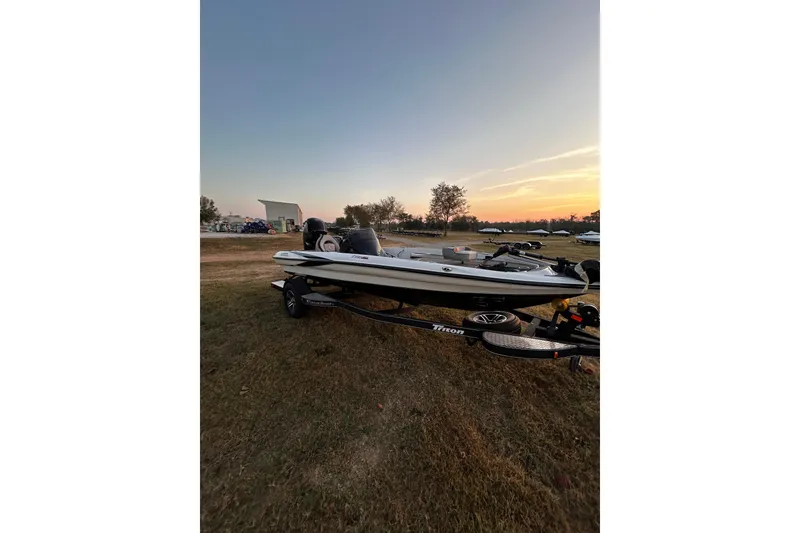 Slide: The Image of 2024 Triton 179 TrX boat on trailer at sunset, parked on grassy field. - 23