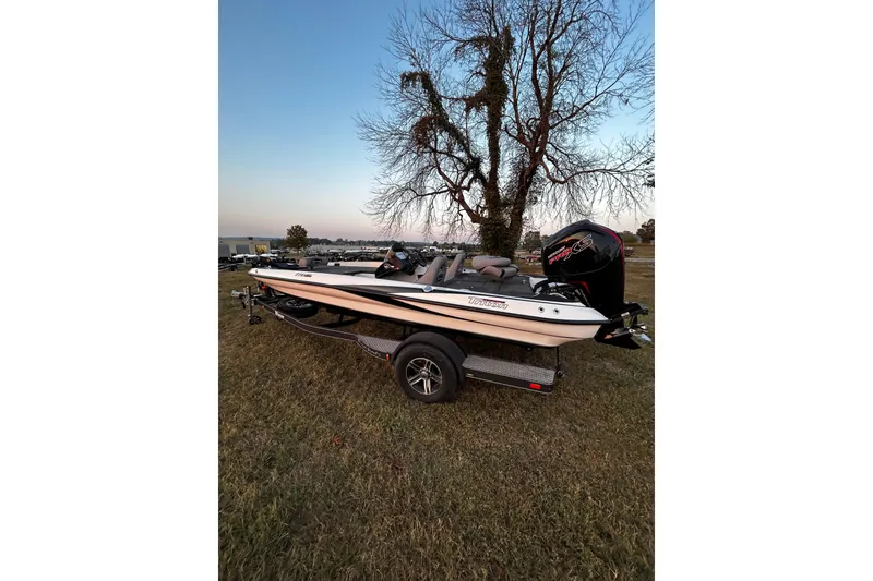 Slide: The Image of 2024 Triton 179 TrX boat on trailer, parked on grass near a tree at sunset. - 25