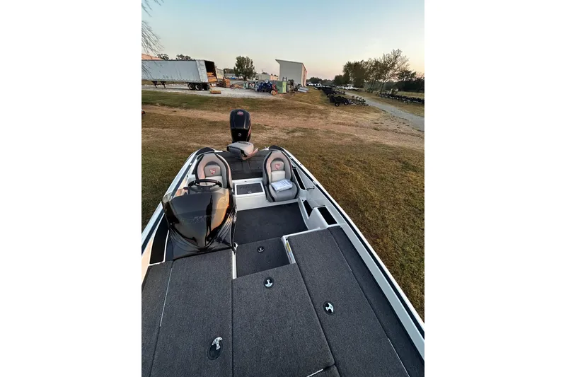 Slide: The Image of 2024 Triton 179 TrX boat with dual seats and motor, parked on grassy area. - 3