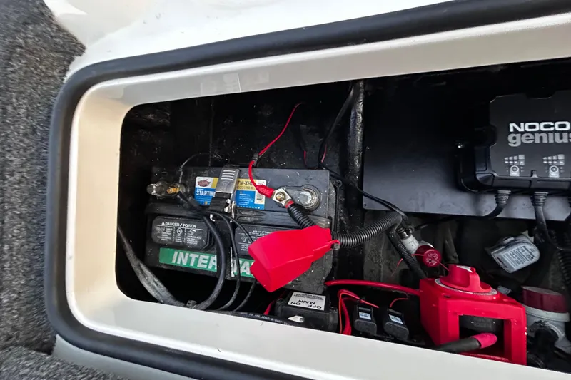 Slide: The Image of 2024 Triton 179 TrX boat battery compartment with wiring and Noco Genius charger. - 6