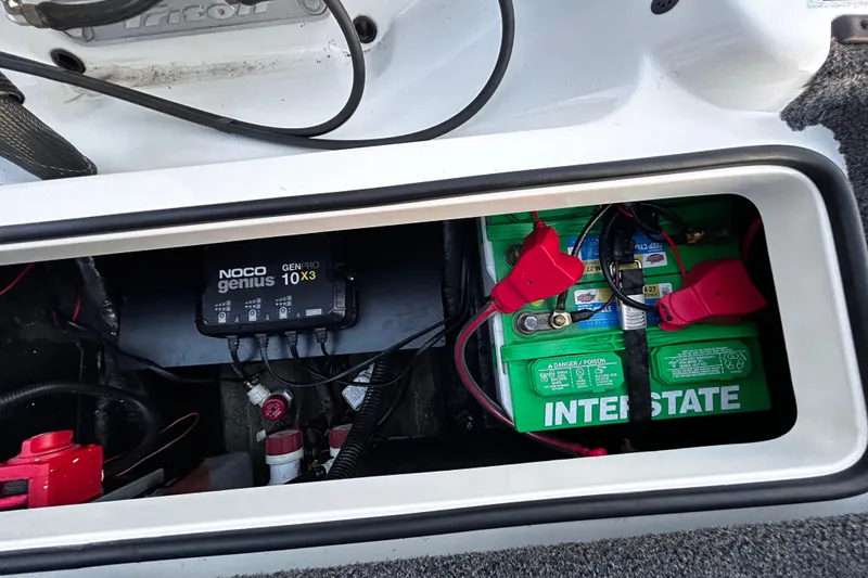 Slide: The Image of 2024 Triton 179 TrX boat battery compartment with NOCO Genius charger and Interstate batteries. - 7