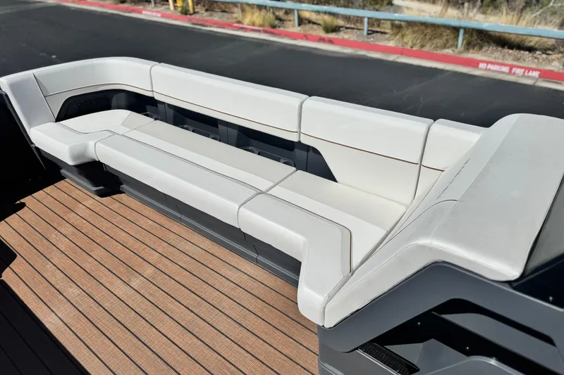 Slide: The Image of Luxurious seating on 2025 Manitou EXPLORE 26 boat, featuring sleek white upholstery and wooden flooring. - 11
