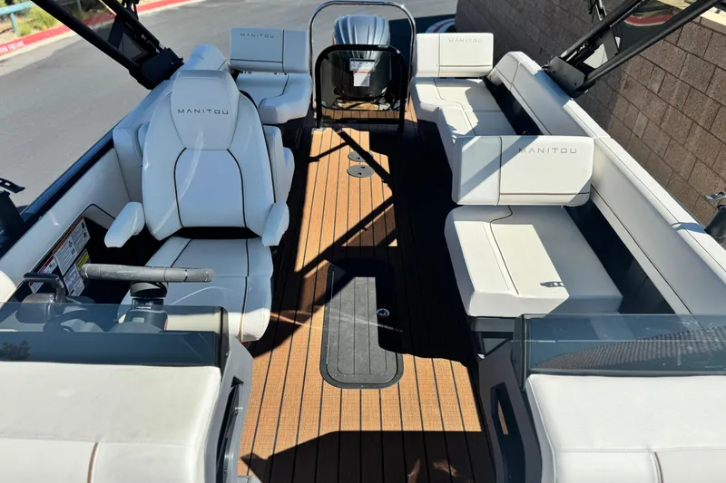 Slide: The Image of 2025 Manitou EXPLORE 26 boat interior with white seating and wooden flooring. - 12