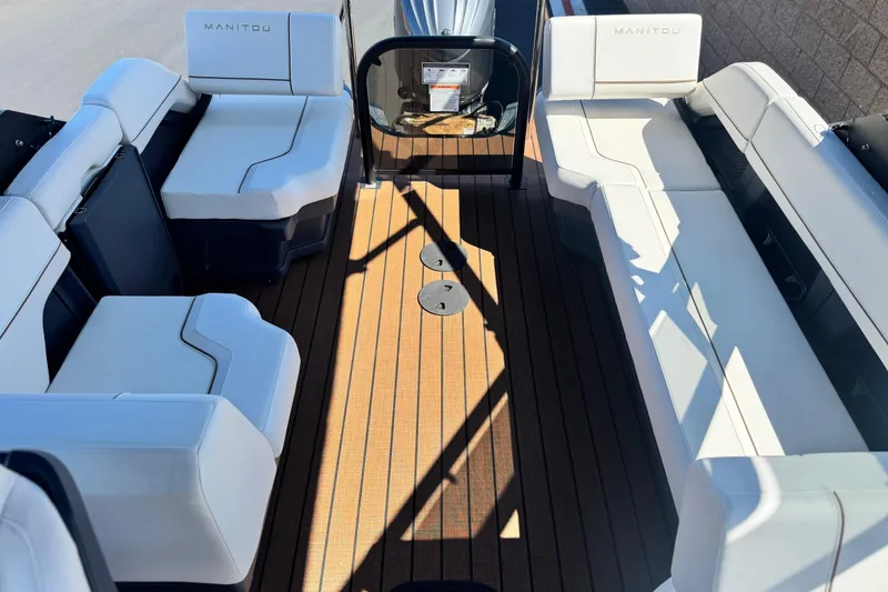 Slide: The Image of 2025 Manitou EXPLORE 26 boat interior with white seating and wooden deck. - 13