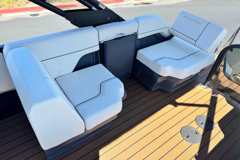 Slide: The Image of Interior seating of 2025 Manitou EXPLORE 26 boat with white cushions and wooden flooring. - 15