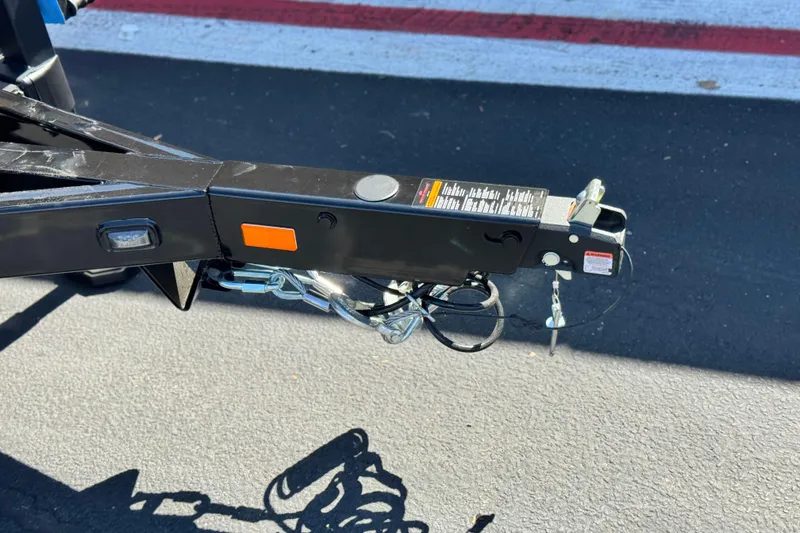 Slide: The Image of Trailer hitch of 2025 Manitou EXPLORE 26 on asphalt, featuring safety chains and warning labels. - 27