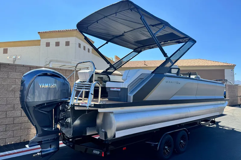 Slide: The Image of 2025 Manitou EXPLORE 26 pontoon boat with Yamaha engine, parked outdoors. - 6