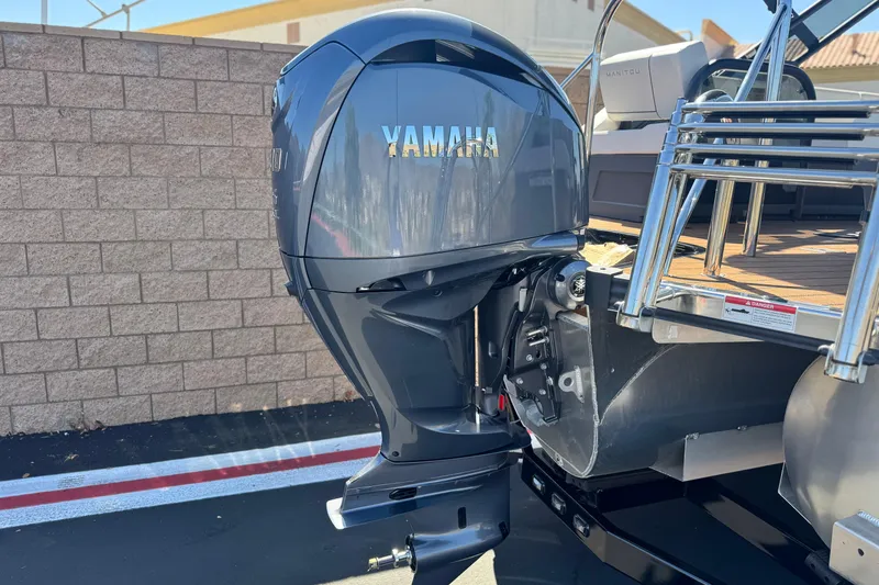 Slide: The Image of 2025 Manitou EXPLORE 26 with Yamaha outboard motor, parked near a brick wall. - 7