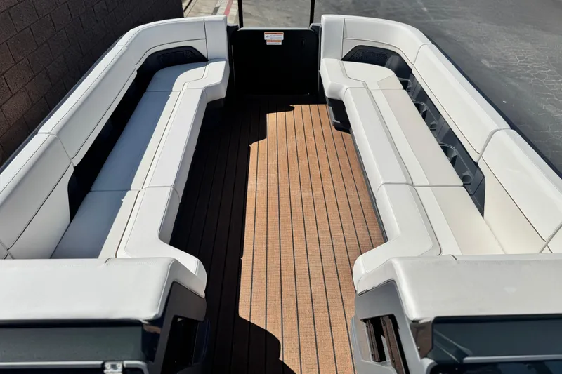 Slide: The Image of 2025 Manitou EXPLORE 26 boat interior with white seating and wooden deck. - 9