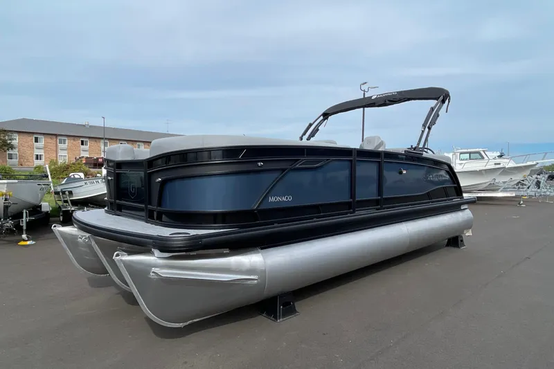 Slide: The Image of 2026 Godfrey Monaco 235 SB pontoon boat parked on asphalt under a cloudy sky. - 3