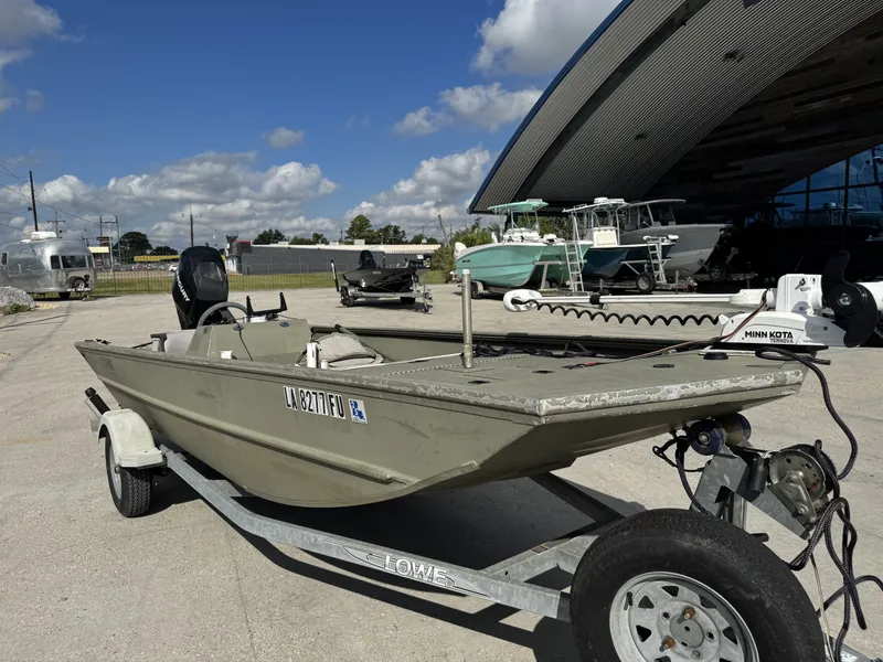 Slide: The Image of 2009 Lowe R1655SC boat on trailer, parked outside a modern building under a clear blue sky. - 11