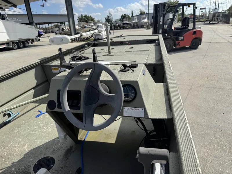 Slide: The Image of 2009 Lowe R1655SC boat interior with steering wheel, parked near forklift and boats. - 6