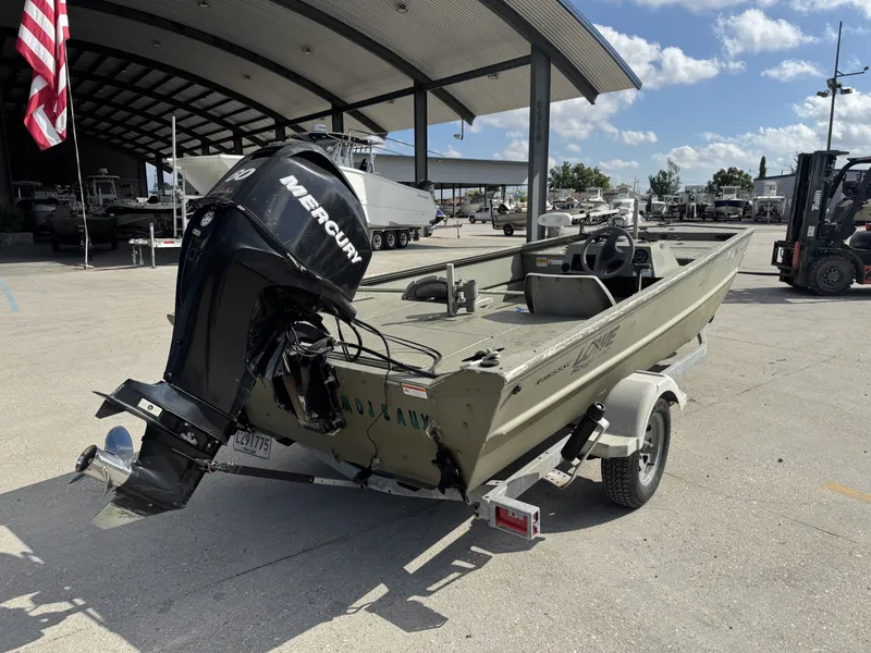 Slide: The Image of 2009 Lowe R1655SC boat with Mercury engine on trailer, parked outdoors under a canopy. - 8