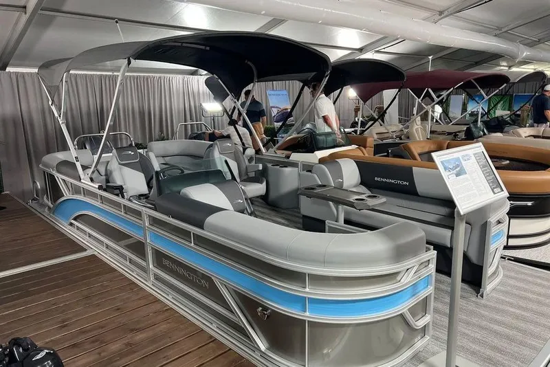 Slide: The Image of 2026 Bennington SSR pontoon boat displayed indoors with modern seating and canopy. - 5