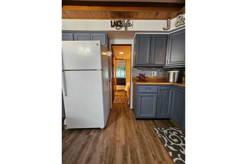 Slide: The Image of Kitchen interior of 1985 Sumerset 14x60 houseboat with gray cabinets and wood flooring. - 11