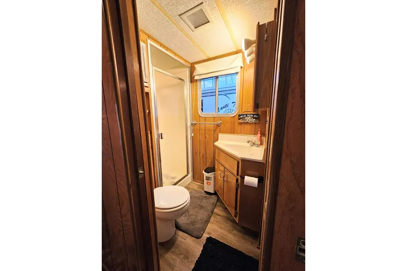 Slide: The Image of 1985 Sumerset 14x60 houseboat bathroom with shower, toilet, and wooden cabinetry. - 13