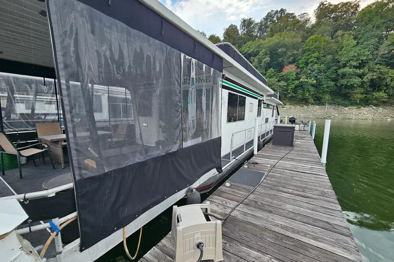 Slide: The Image of 1985 Sumerset 14x60 houseboat docked on a serene lake with lush greenery. - 2