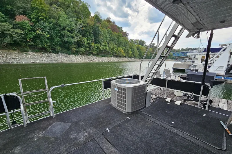 Slide: The Image of 1985 Sumerset 14x60 houseboat docked on a serene lake with lush green surroundings. - 25