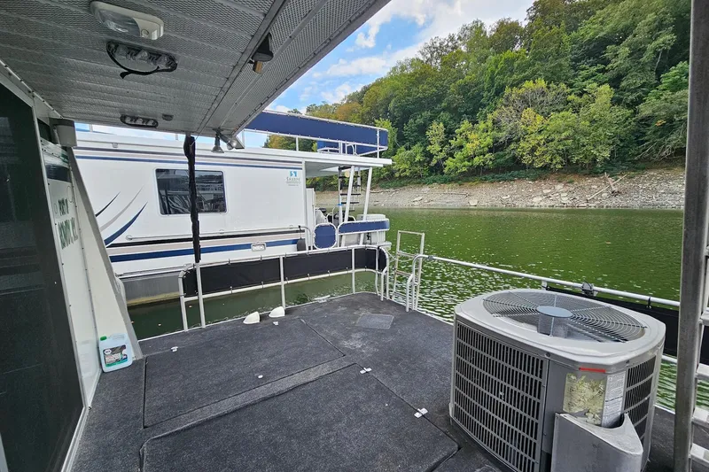 Slide: The Image of 1985 Sumerset 14x60 houseboat docked on a serene lake with lush green trees. - 26