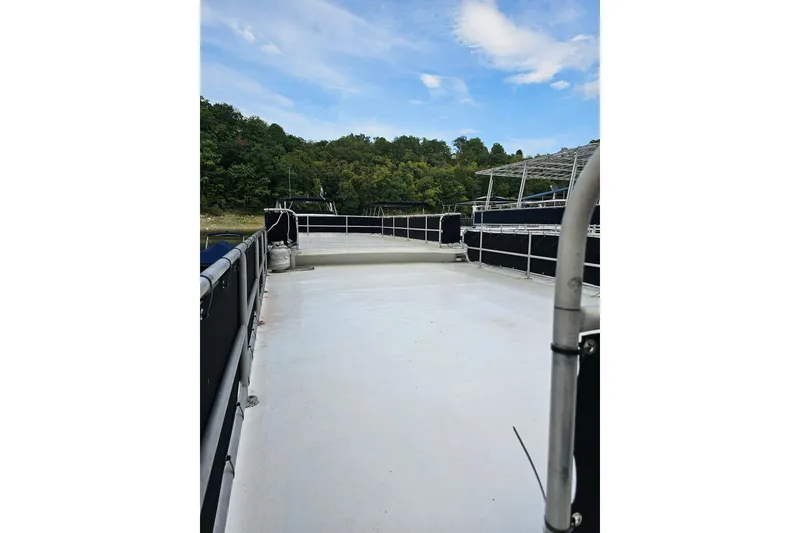 Slide: The Image of 1985 Sumerset 14x60 houseboat deck with railing, surrounded by trees and blue sky. - 29