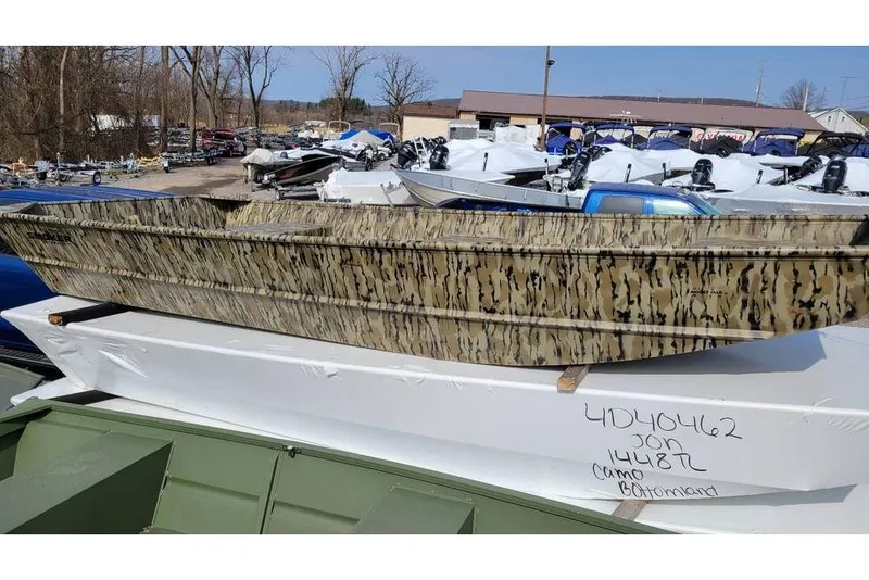 The Image of 2025 Smoker Craft 1448 jon boat with camo design, displayed outdoors. - 1