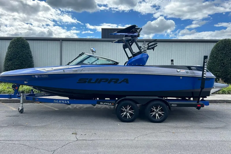 Slide: The Image of 2014 Supra SA 450 boat in blue on a trailer, parked outdoors under a cloudy sky. - 3