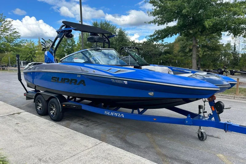 Slide: The Image of Blue 2014 Supra SA 450 boat on trailer, parked outdoors under a clear sky. - 6