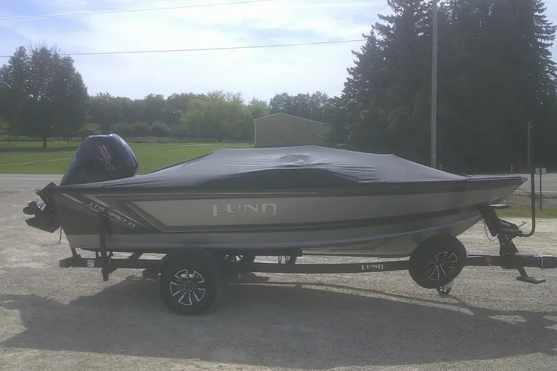 Slide: The Image of 2026 Lund 1775 Impact XS SS boat on trailer, covered, outdoors. - 12